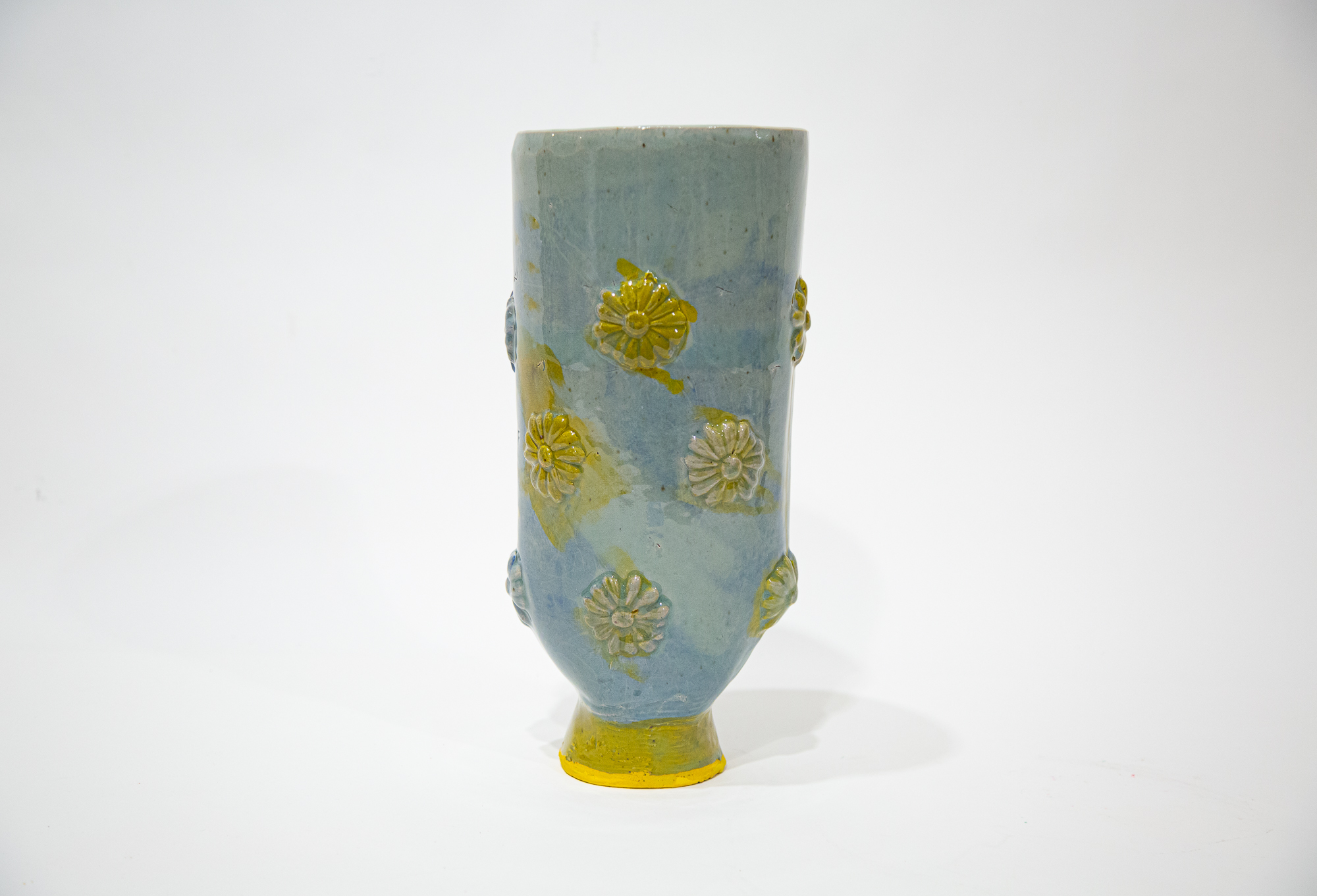 Photograph of a blue and yellow ceramic vase with sprigged relief florets stained in a yellow wash.